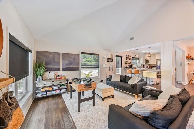 living area featuring high vaulted ceiling, visible vents, and wood finished floors