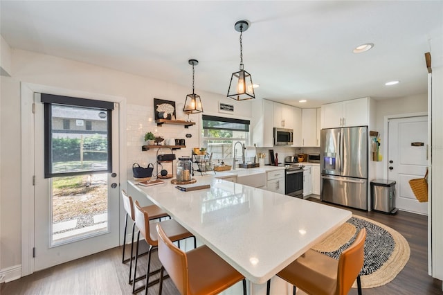kitchen with a peninsula, tasteful backsplash, a kitchen bar, light countertops, and appliances with stainless steel finishes