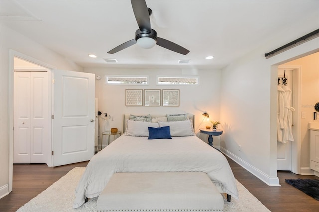 bedroom featuring baseboards, dark wood-style flooring, visible vents, and a barn door