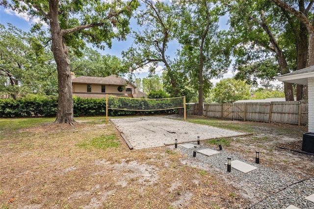 view of yard with volleyball court and fence
