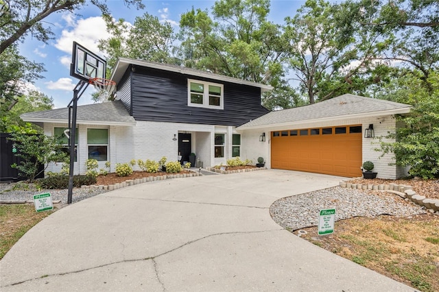 view of front of house featuring roof with shingles, a garage, brick siding, and driveway