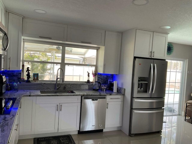 11727 Spanish Lake Dr, Tampa, FL 33635 - kitchen featuring a healthy amount of sunlight, white cabinetry, light stone counters, a sink, and stainless steel appliances