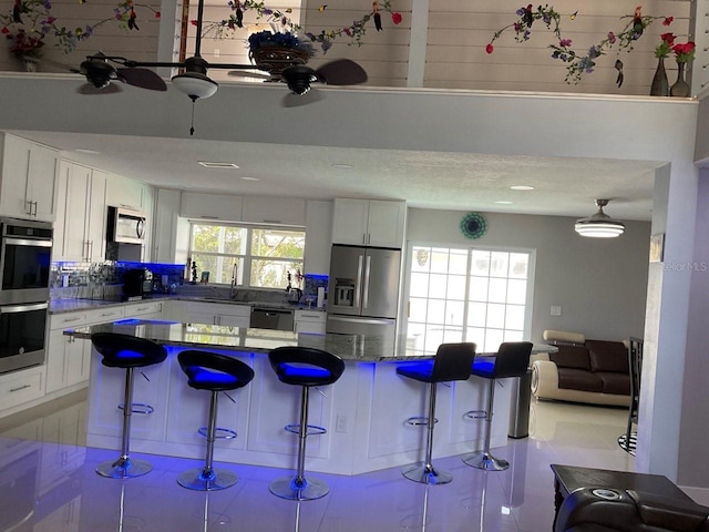 11727 Spanish Lake Dr, Tampa, FL 33635 - kitchen featuring a ceiling fan, a kitchen bar, a sink, white cabinets, and stainless steel appliances
