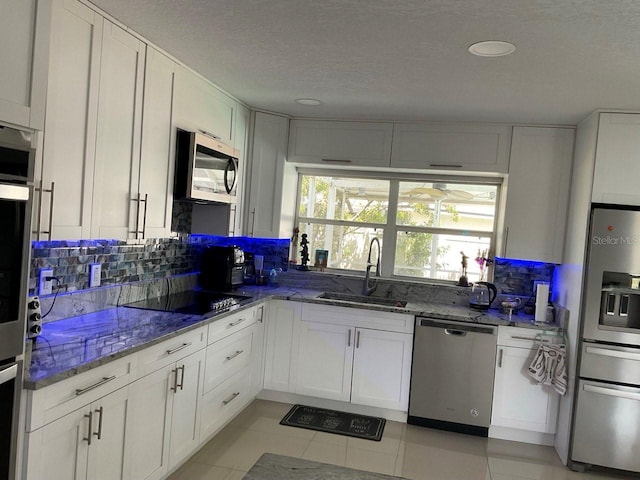 11727 Spanish Lake Dr, Tampa, FL 33635 - kitchen featuring decorative backsplash, appliances with stainless steel finishes, a sink, white cabinets, and stone counters