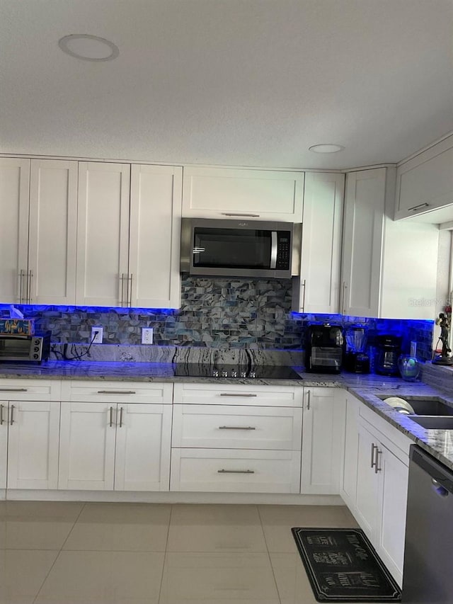 11727 Spanish Lake Dr, Tampa, FL 33635 - kitchen with light stone counters, stainless steel appliances, white cabinetry, light tile patterned floors, and backsplash