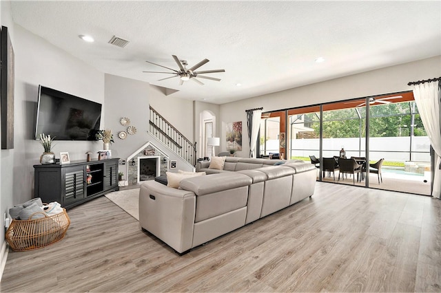 living room featuring a ceiling fan, light wood-style flooring, recessed lighting, visible vents, and stairs