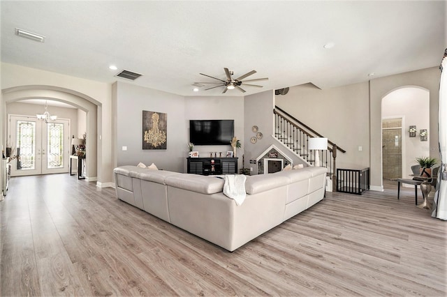 living area with light wood finished floors, visible vents, french doors, and arched walkways
