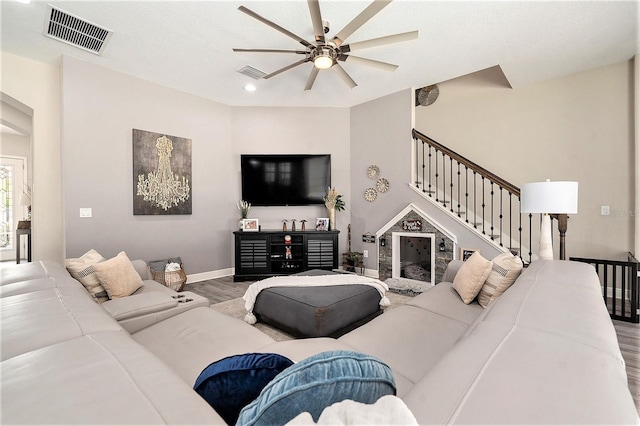 living room with baseboards, a ceiling fan, visible vents, and wood finished floors