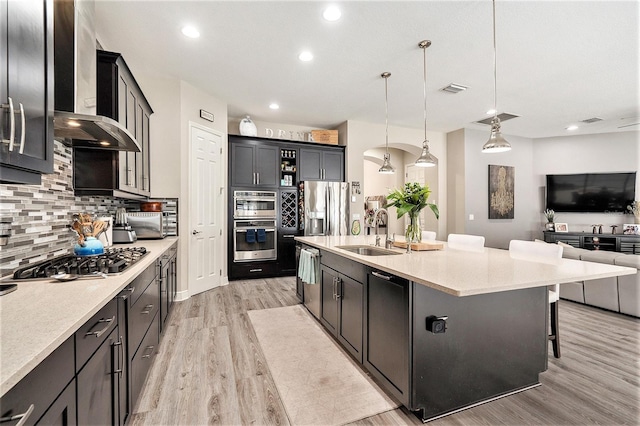 kitchen with a sink, light wood-style flooring, decorative backsplash, and appliances with stainless steel finishes