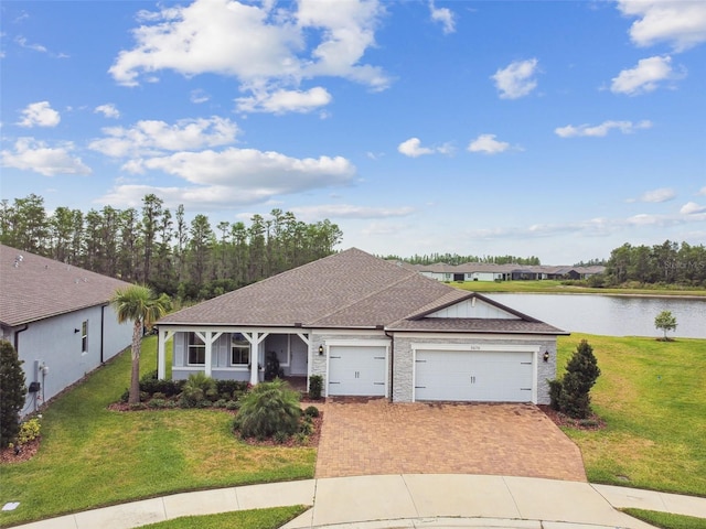 5670 Shorebird Br, Land O Lakes, FL 34638 - ranch-style house featuring a water view, an attached garage, a front yard, decorative driveway, and a shingled roof