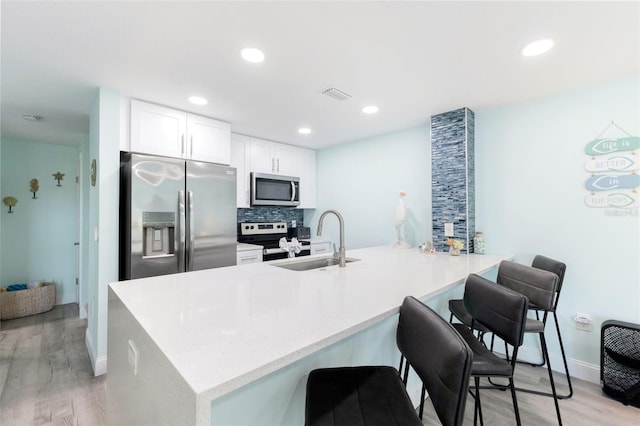 337 Rex Pl Unit G, Madeira Beach, FL 33708 - kitchen with a sink, a peninsula, a kitchen breakfast bar, light wood-type flooring, and appliances with stainless steel finishes
