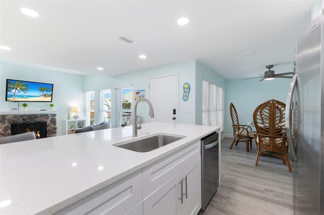 337 Rex Pl Unit G, Madeira Beach, FL 33708 - kitchen featuring light wood finished floors, a sink, stainless steel appliances, open floor plan, and a stone fireplace