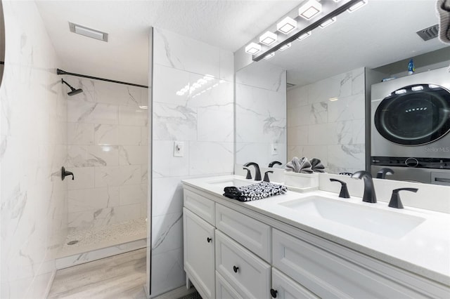 337 Rex Pl Unit G, Madeira Beach, FL 33708 - bathroom featuring walk in shower, a sink, tile walls, stacked washer / drying machine, and visible vents