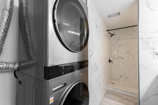 337 Rex Pl Unit G, Madeira Beach, FL 33708 - laundry room featuring visible vents, laundry area, stacked washer and clothes dryer, and wood finished floors