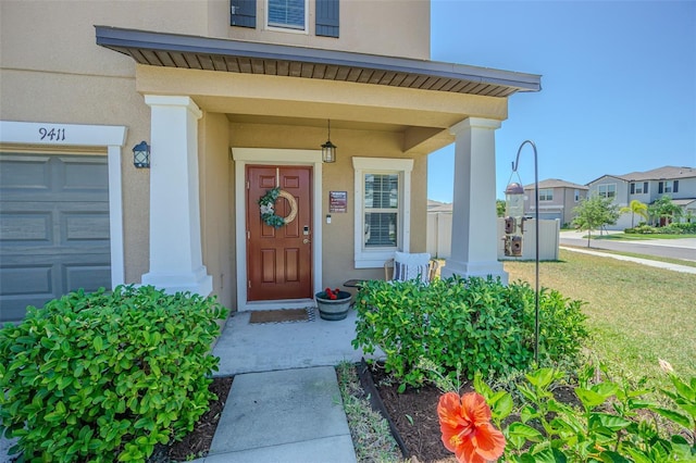 property entrance with stucco siding, a residential view, covered porch, and an attached garage
