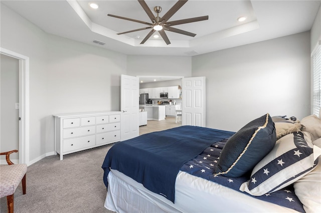 bedroom featuring a tray ceiling, recessed lighting, freestanding refrigerator, light carpet, and ceiling fan