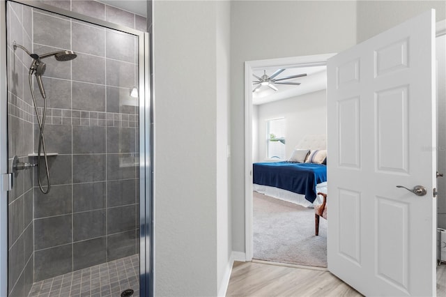 bathroom with a shower stall, connected bathroom, wood finished floors, a ceiling fan, and baseboards