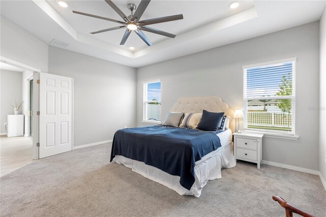 carpeted bedroom with a tray ceiling, recessed lighting, baseboards, and a ceiling fan