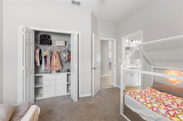 bedroom with a closet, light carpet, baseboards, and ensuite bath