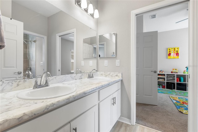 full bathroom featuring double vanity, baseboards, and a shower