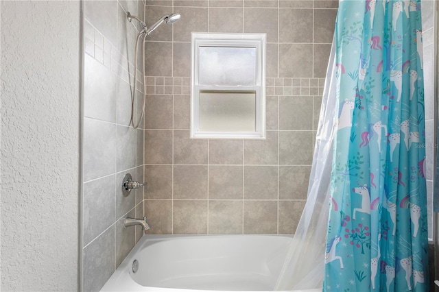 bathroom with shower / bath combination with curtain and a textured wall