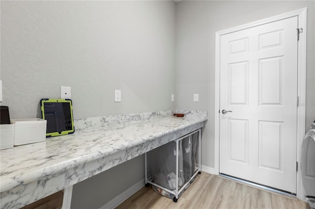 laundry room with light wood finished floors, baseboards, and washer and clothes dryer