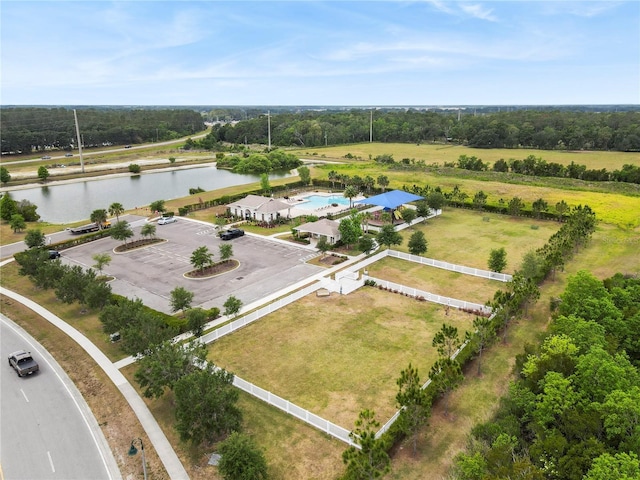aerial view of a nearby body of water, a pool, and a tree filled landscape