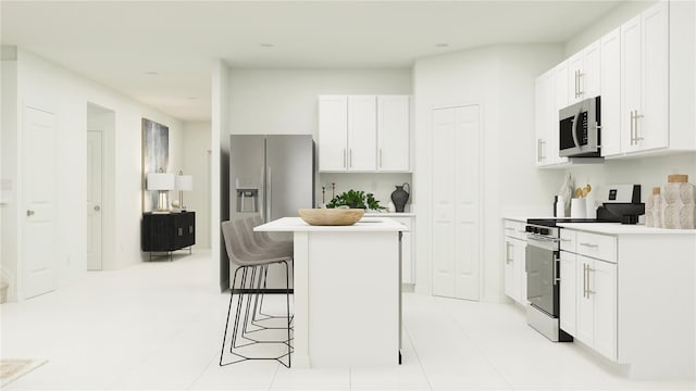 kitchen with a kitchen breakfast bar, a center island, light countertops, white cabinets, and stainless steel appliances