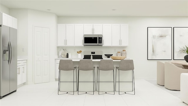kitchen with a breakfast bar area, appliances with stainless steel finishes, a center island, light countertops, and white cabinetry