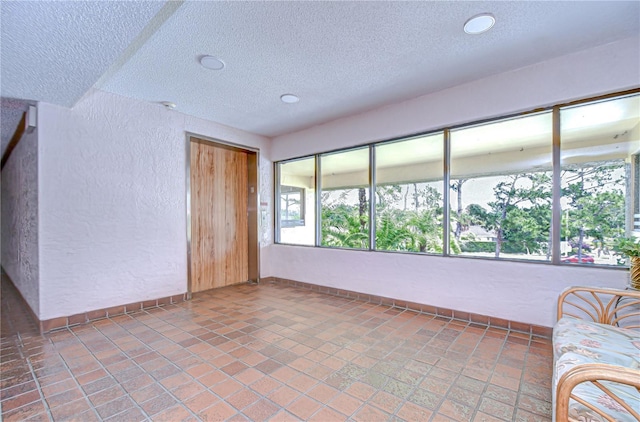 unfurnished living room with baseboards, recessed lighting, a textured ceiling, and a textured wall