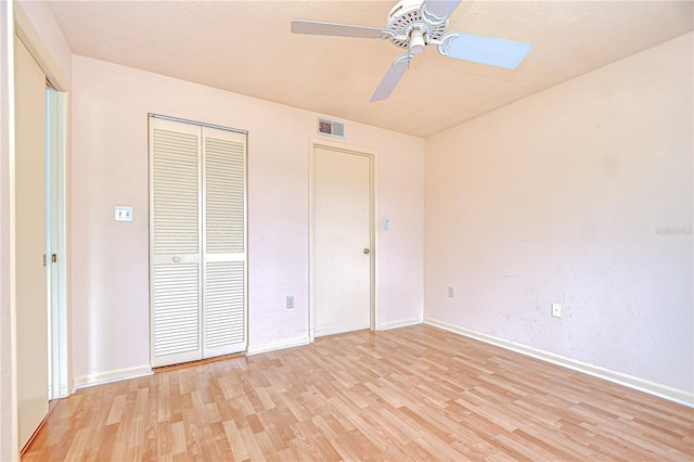 unfurnished bedroom featuring a closet, visible vents, baseboards, ceiling fan, and light wood-style floors