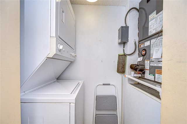 washroom featuring stacked washer and dryer, laundry area, and a textured ceiling