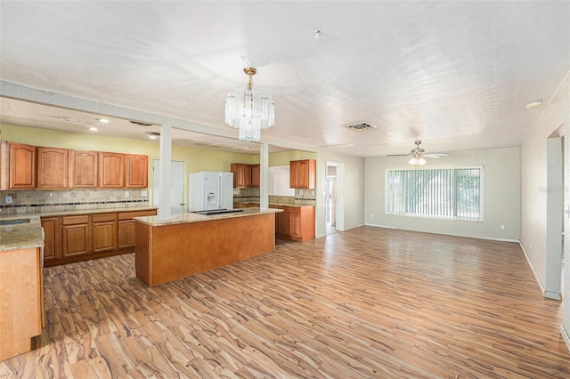 kitchen with white refrigerator with ice dispenser, light wood-style flooring, backsplash, and open floor plan