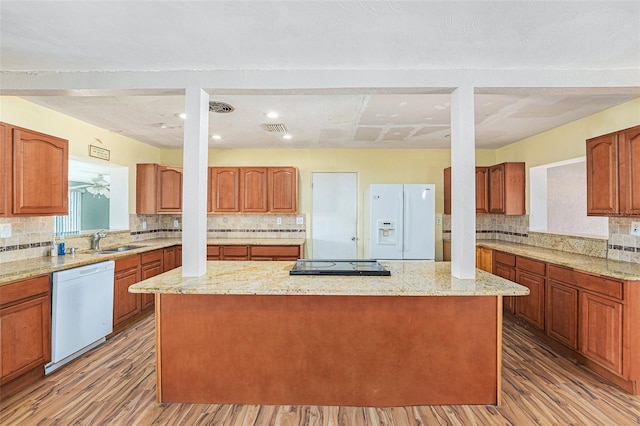 kitchen with a center island, wood finished floors, a sink, and white appliances