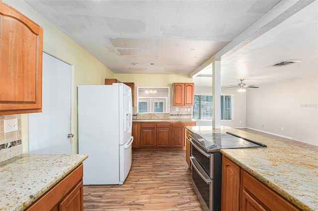kitchen with range with two ovens, light wood finished floors, tasteful backsplash, and white fridge with ice dispenser