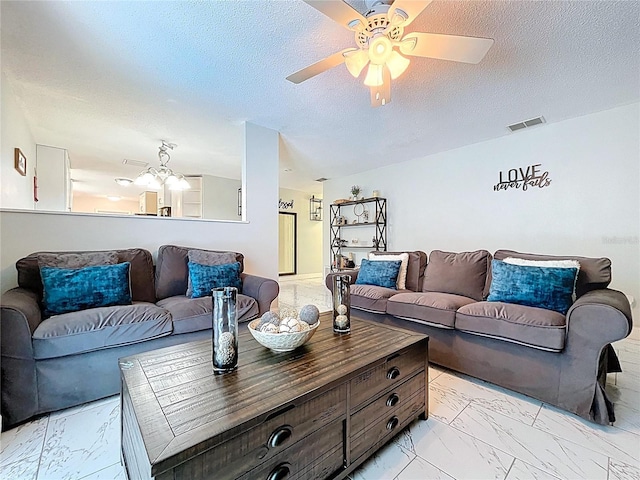 living room featuring a textured ceiling, ceiling fan with notable chandelier, marble finish floor, and visible vents