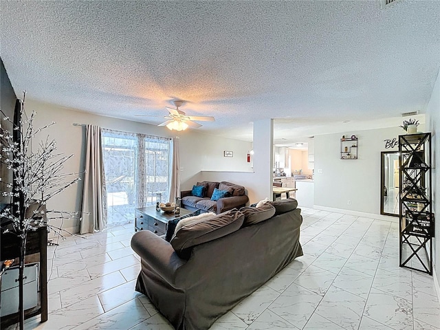 living area with a textured ceiling, marble finish floor, and ceiling fan