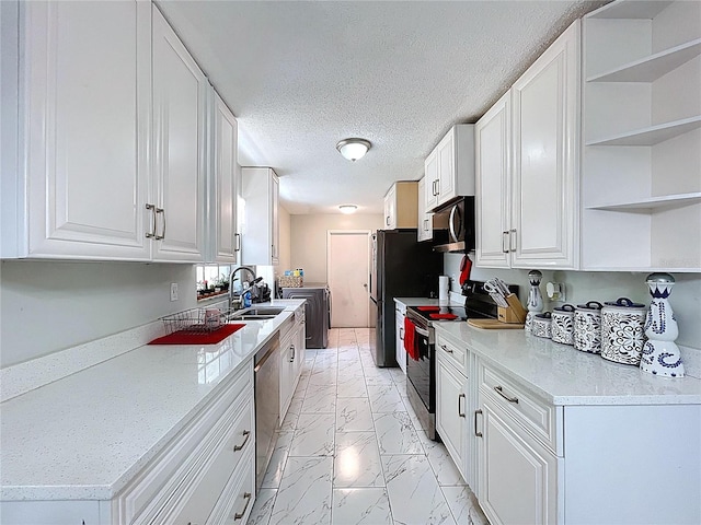 kitchen featuring independent washer and dryer, marble finish floor, a sink, white cabinetry, and stainless steel appliances