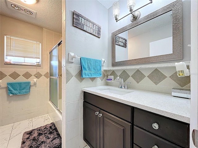 full bath featuring tile walls, a textured ceiling, marble finish floor, and vanity