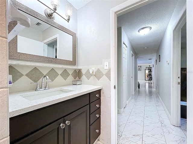 bathroom featuring vanity, a textured ceiling, marble finish floor, and visible vents