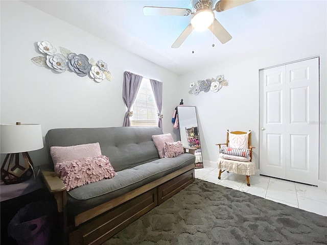 living area featuring marble finish floor and ceiling fan