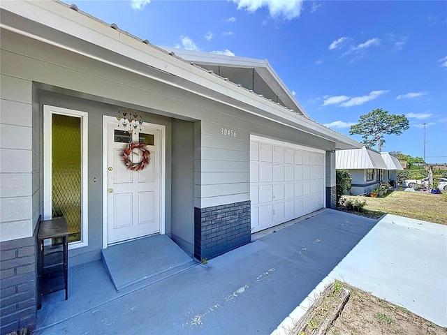 property entrance featuring a garage and brick siding