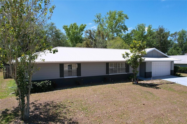 single story home with metal roof, concrete driveway, a garage, and a front yard