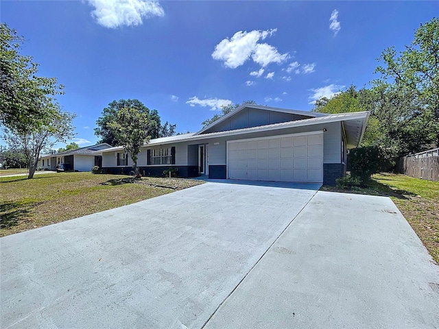 ranch-style home with a garage, fence, concrete driveway, board and batten siding, and a front yard