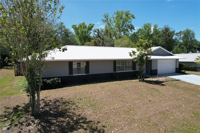 ranch-style house featuring concrete driveway, metal roof, a front lawn, and a garage