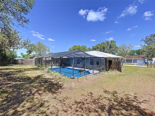view of swimming pool featuring a lawn, a fenced in pool, a fenced backyard, and a lanai