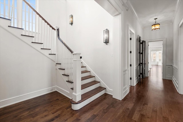 staircase with wood finished floors, baseboards, and ornamental molding