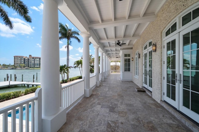 balcony with a water view, french doors, and ceiling fan