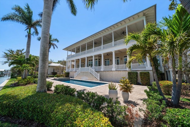 rear view of property with stairway, a ceiling fan, and an outdoor pool