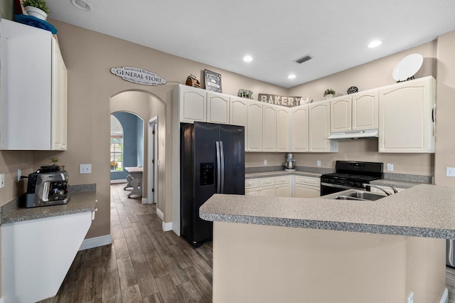 kitchen featuring dark wood-type flooring, visible vents, black appliances, arched walkways, and under cabinet range hood